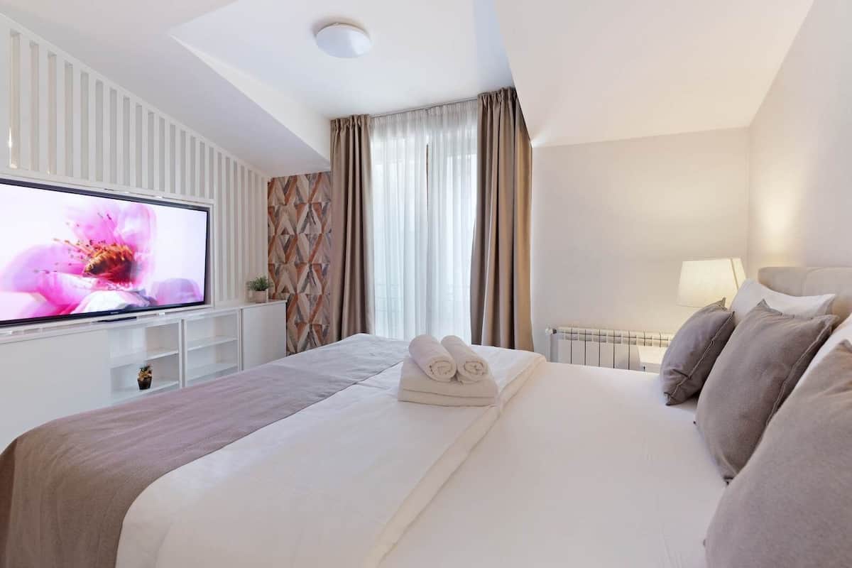 Ein Hotelzimmer mit Bett, Fernseher, Heizkörper und Vorhängen.