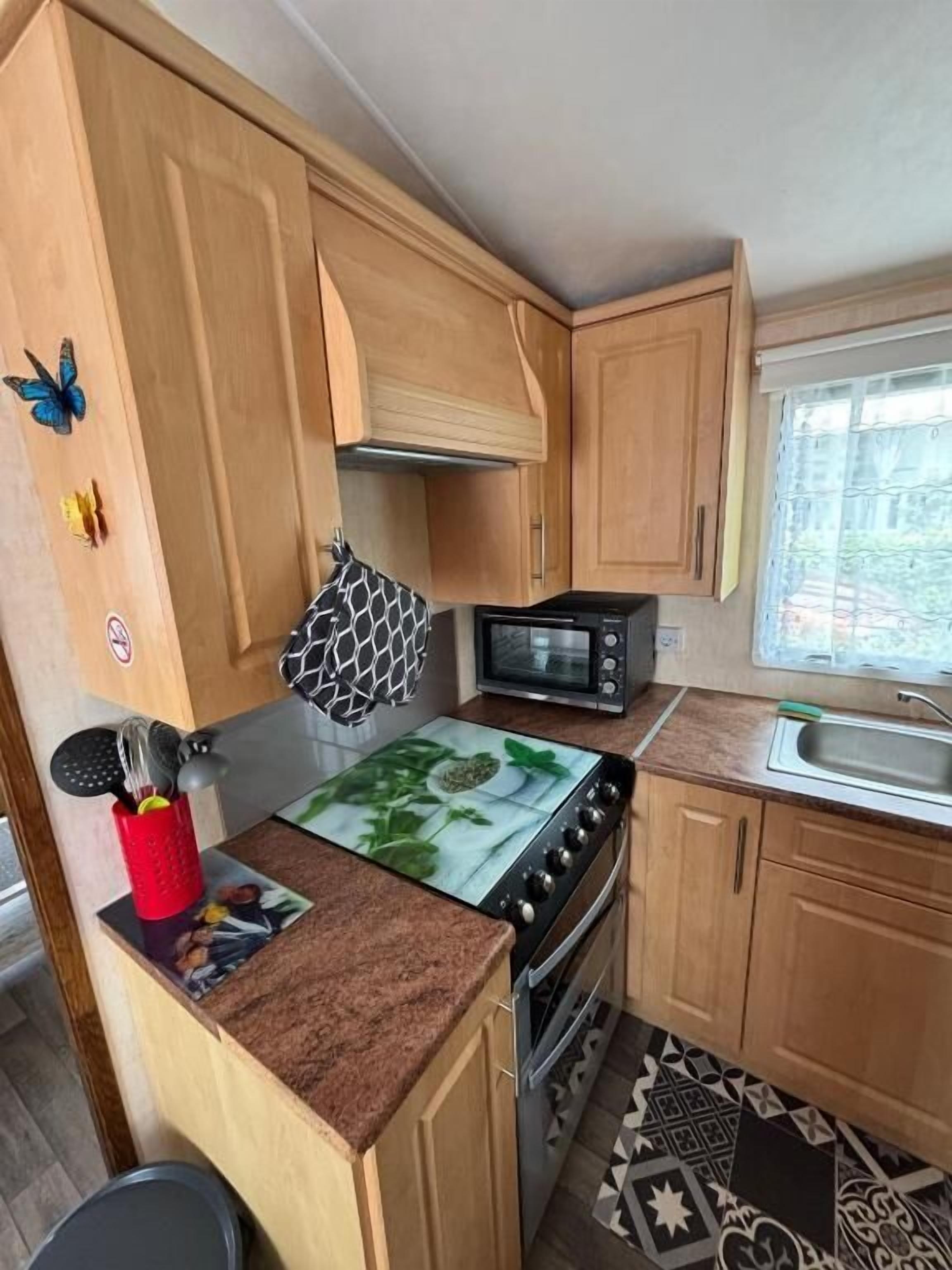 Une cuisine de taille réduite, dotée de meubles en bois, d’un four à micro-ondes, d’une cuisinière et d’un évier.