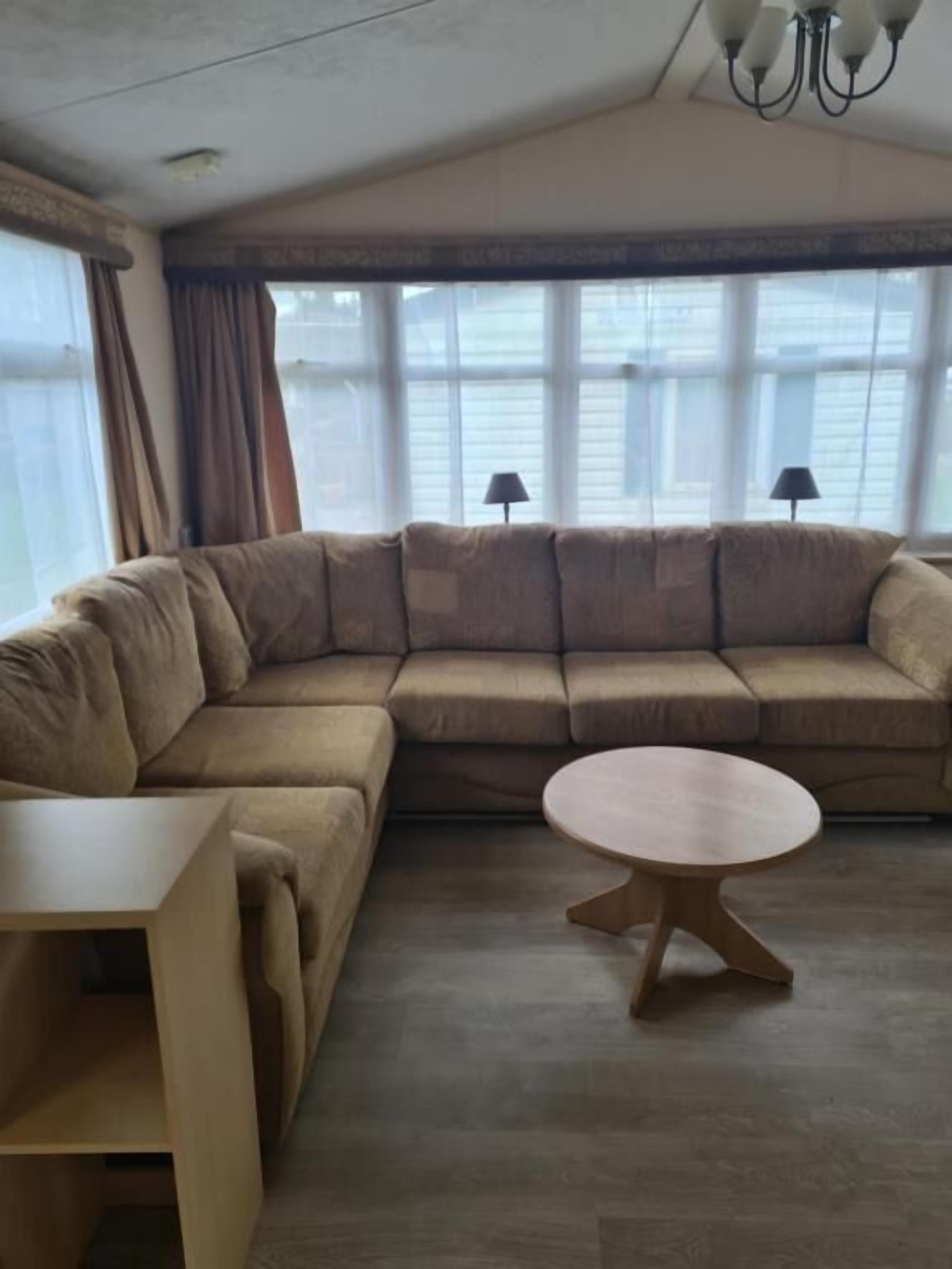 A modern living room with a large L-shaped sectional sofa, a round coffee table, and a small side table.