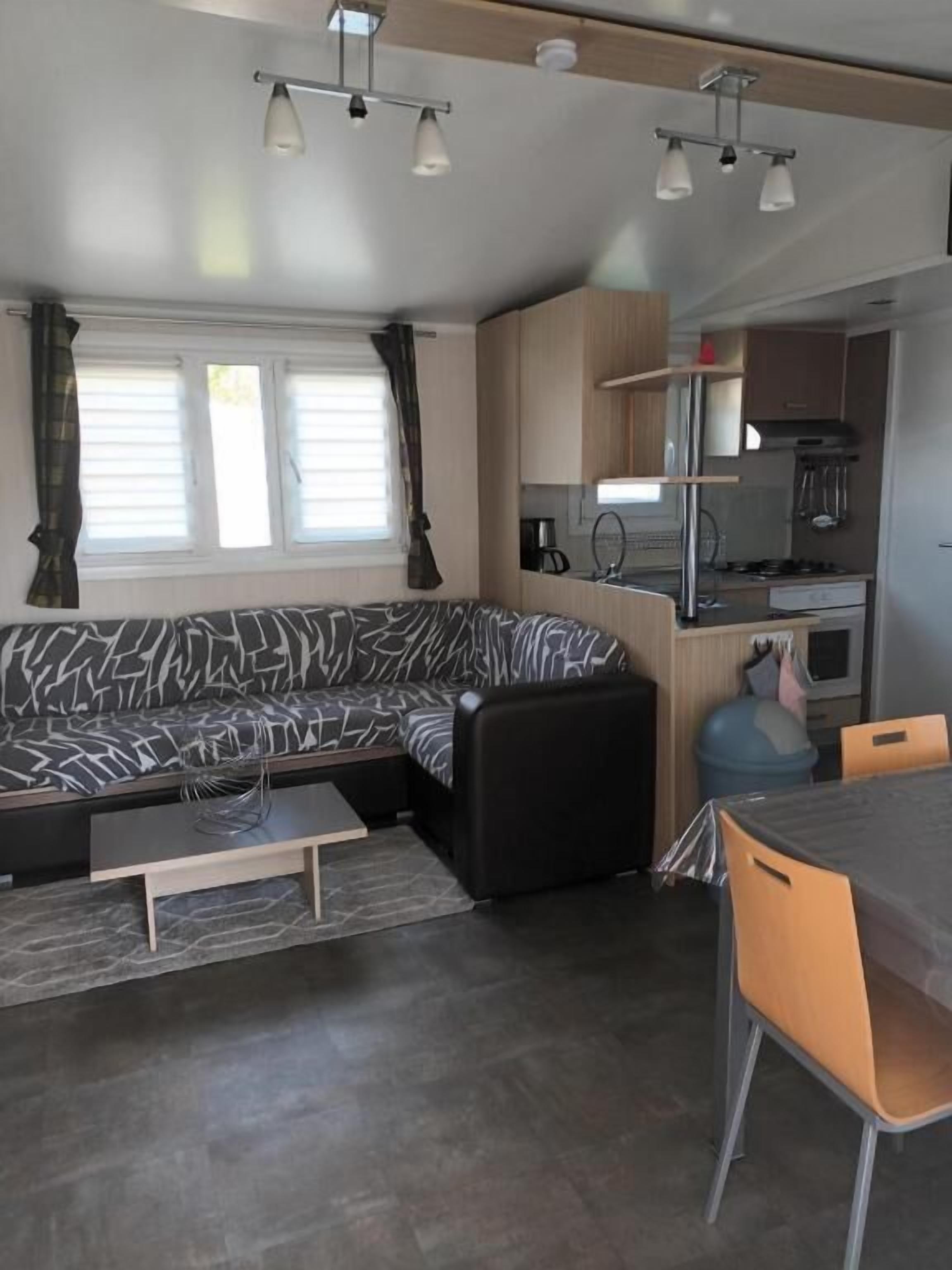 A compact living space with a sofa, a dining table, and a kitchenette.