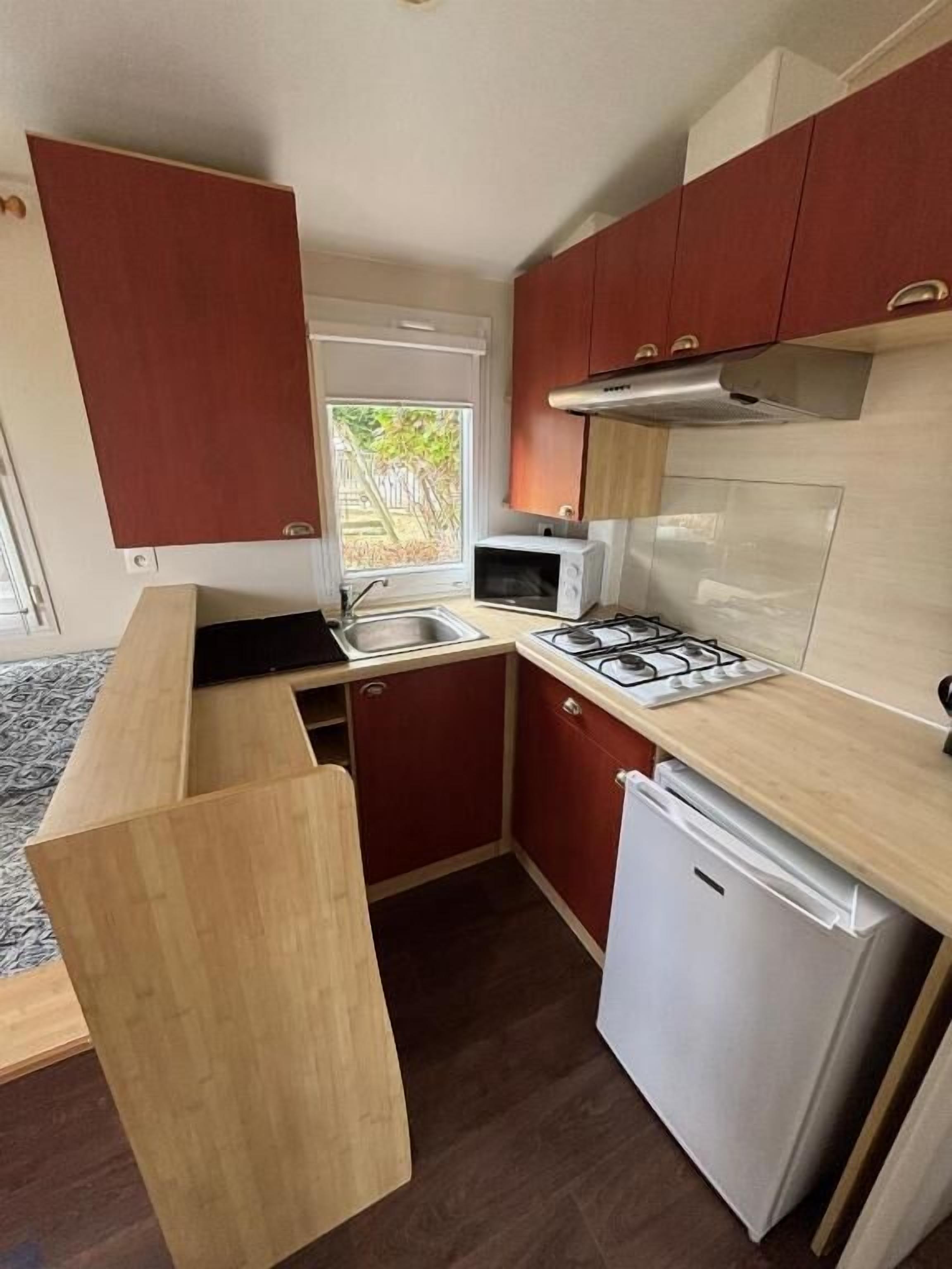 Una cocina compacta con microondas, estufa, fregadero y un refrigerador pequeño.
