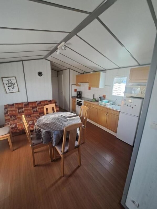 Une cuisine compacte avec des meubles en bois, une table à manger avec des chaises et un luminaire fixé au mur.