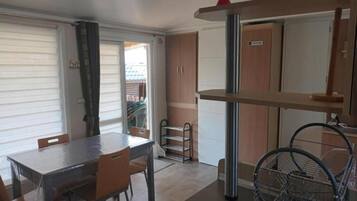 A compact kitchen with a dining table, chairs, a metal rack, and a door with a sign.