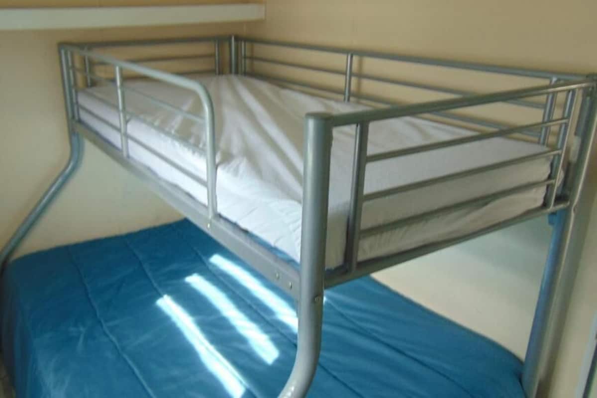 A bunk bed with a blue mattress and metal railings.