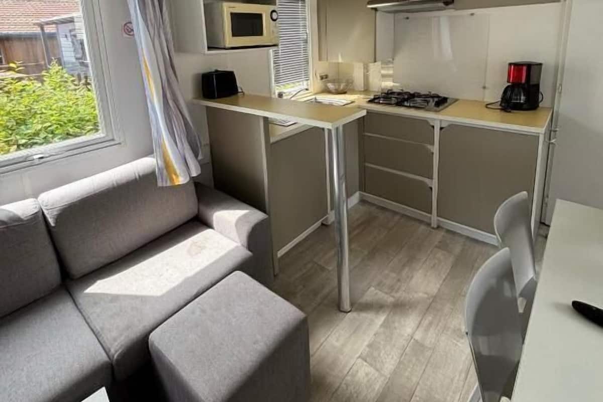 A compact kitchenette with a microwave, stove, and coffee maker. There is a small dining table and a sofa in the living area.
