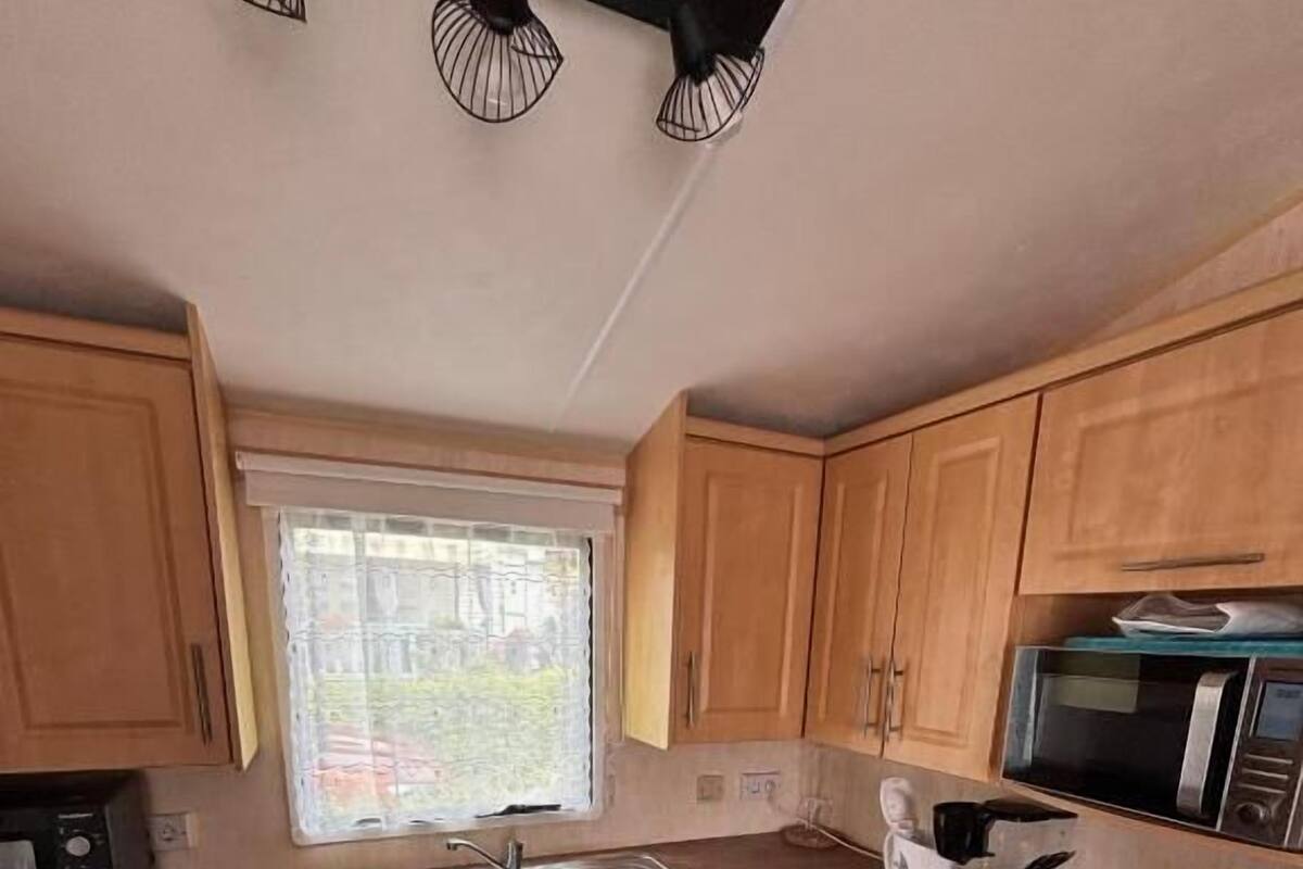 A compact kitchen with wooden cabinets, a microwave, a sink, a stove, and a refrigerator.