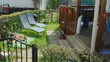 A wooden deck with a metal railing, a small garden area with a lawn, and a wooden fence.
