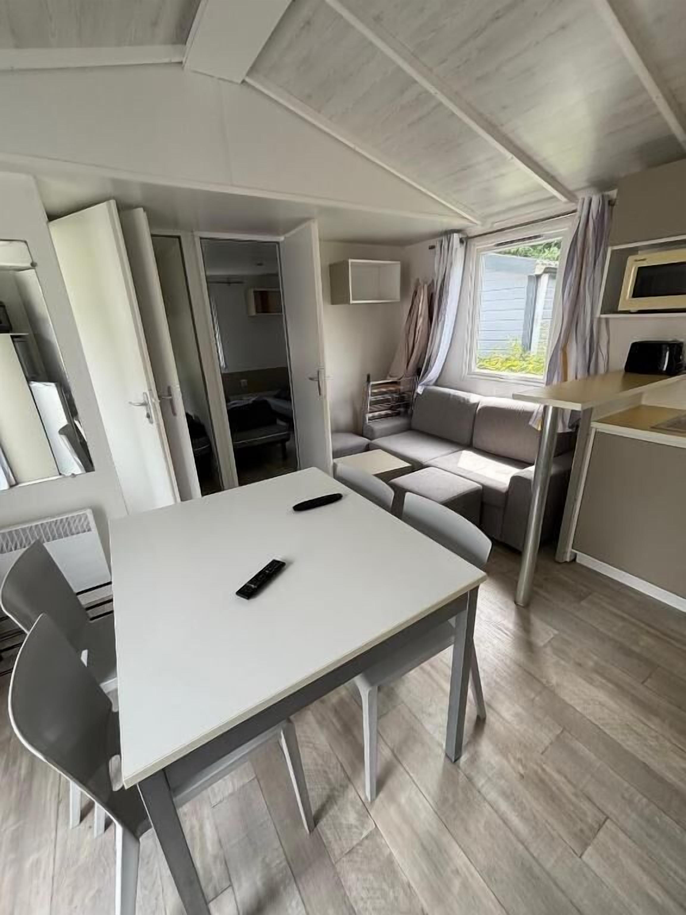 Een compact RV-interieur met een eettafel, een zitbank en een kitchenette.