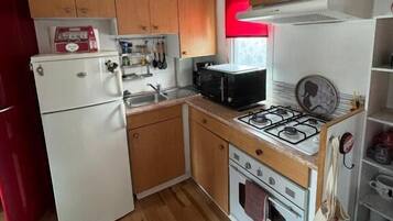Una cocina compacta con armarios de madera, un refrigerador blanco, un microondas, una estufa y un horno.