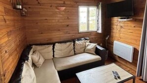 Um quarto acolhedor em estilo cabana, com sofá de canto, uma mesinha e televisão na parede.