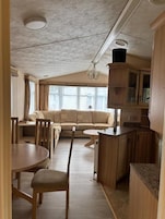 Um espaço compacto com cozinha americana, área de refeições e sala de estar com sofá e cadeiras.