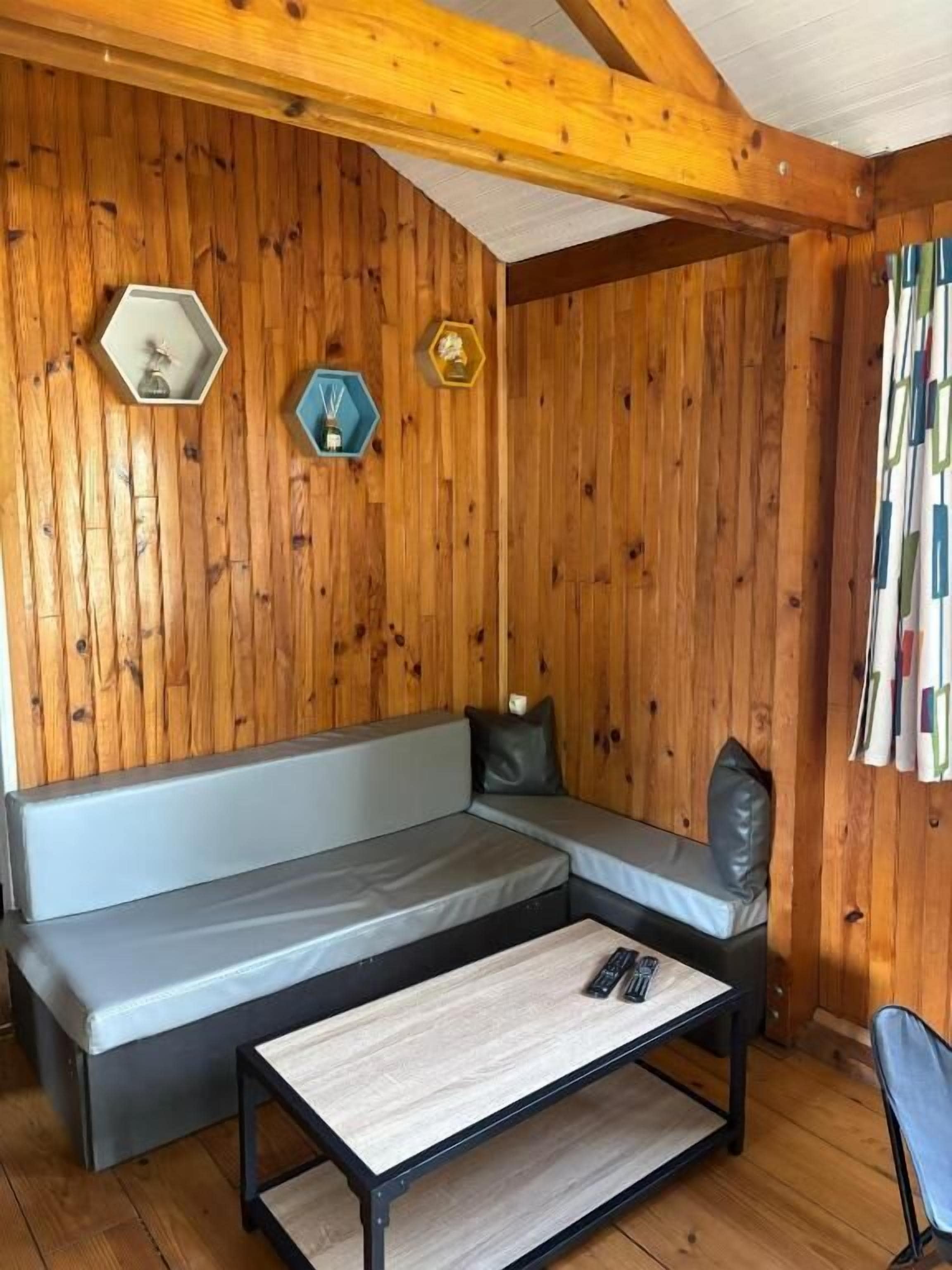 Una habitación acogedora con una pared de madera, un sofá gris, una mesita pequeña y una silla.