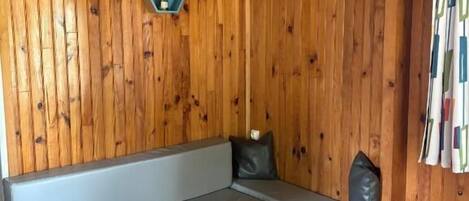 Una habitación acogedora con una pared de madera, un sofá gris, una mesita pequeña y una silla.