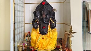 Une statue d’une divinité, placée dans un temple, avec un lustre au-dessus.