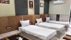 Une chambre d’hôtel avec deux lits simples, une petite table et un climatiseur fixé au mur.