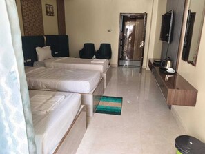 A hotel room with two beds, a TV, a mirror, and a small kitchenette.