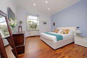 Ein Schlafzimmer mit Bett, Nachttisch, Kommode, Fenster und Spiegel.