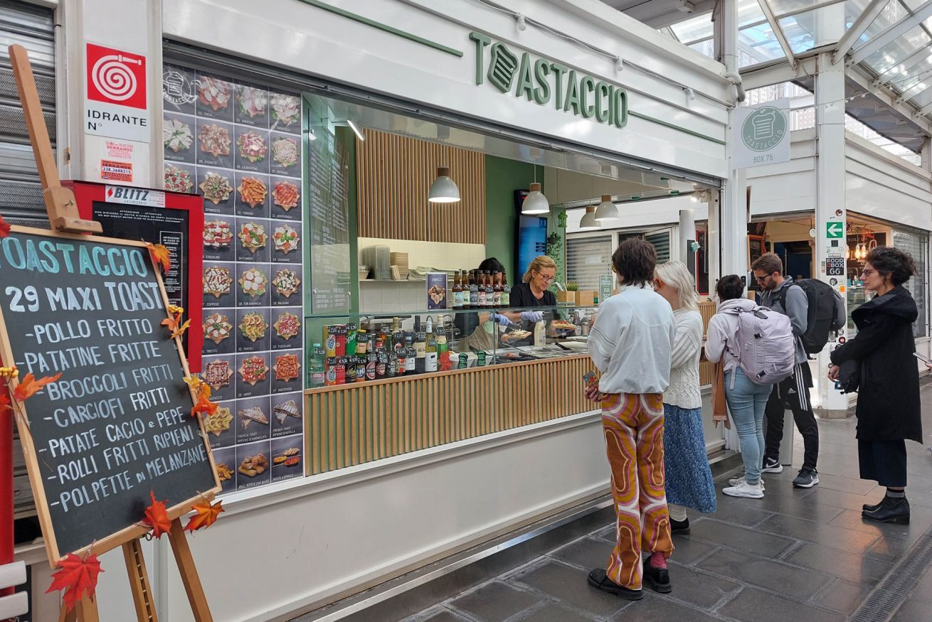 A restaurant named 'TOASTACCIO' with a menu board displaying various dishes.