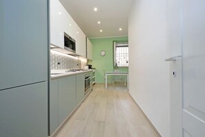 A compact kitchen with modern appliances, a dining area with a table and chairs, and a window with a view. - Bright Apartment in the Heart of Testaccio (roma)