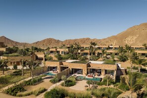 Un resort con varias villas, una piscina y montañas al fondo.