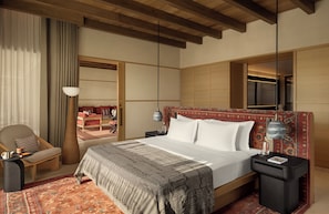 A hotel room with a large bed, a chair, a nightstand, a lamp, and a mirror.