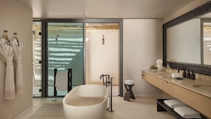 A modern bathroom with a freestanding bathtub, a large mirror, and a glass door leading to a balcony. - Six Senses Amaala (Al Wajh)