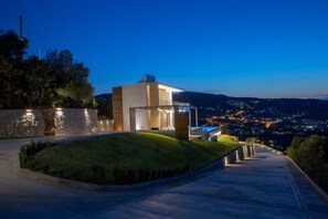 Um edifício moderno com fachada de vidro, base de pedra e entrada bem iluminada.