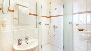 A bathroom with a sink, mirror, and shower area. - Apartment no. 01 (Warnemünde)