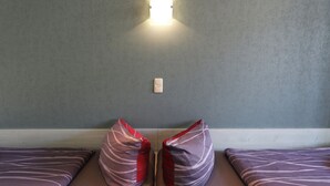 A room with two beds, each with a pillow and a wall-mounted light fixture. - Apartment no. 01 (Warnemünde)