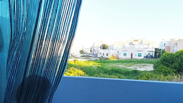 A balcony with a view of residential buildings and a grassy area. - Vacation Home in Otranto with 1 bedrooms sleeps 4 (Otranto)