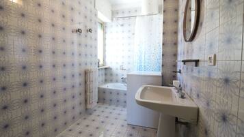 Une salle de bain avec des carreaux décorés, un lavabo, un miroir et un espace douche.