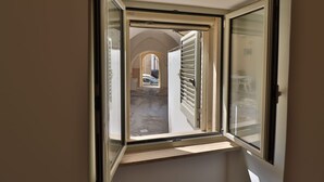A narrow window with a view of an outdoor courtyard and a building with a sloped roof. - Vacation Home in Otranto with 2 bedrooms sleeps 4 (Otranto)