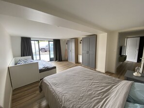 Ein modernes Hotelzimmer mit einem großen Bett, einer Sitzecke, einem Kleiderschrank und Blick ins Freie.