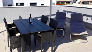 Una terraza en la azotea con mesa y sillas, un toldo blanco y vistas panorámicas de la ciudad.