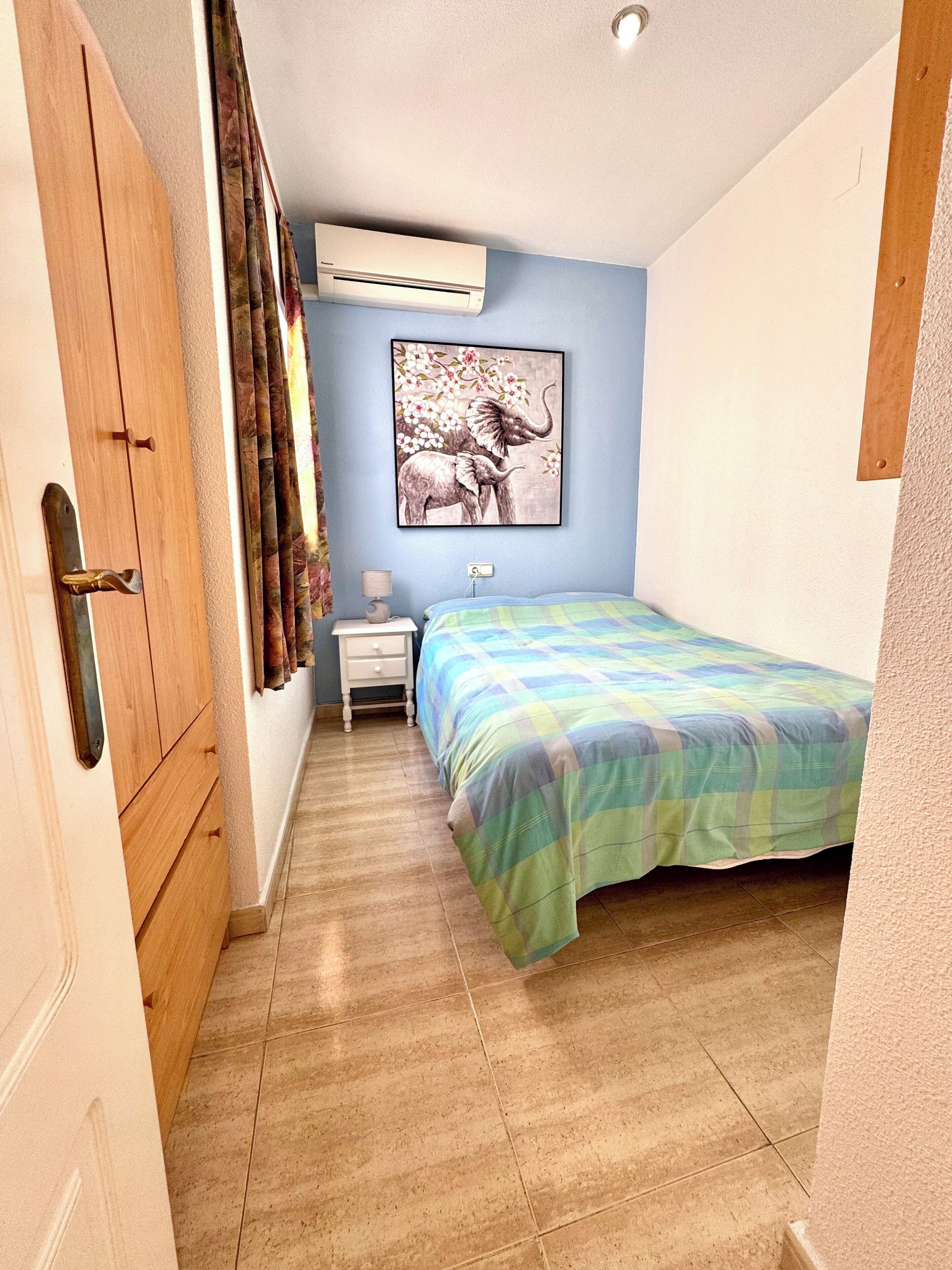 Una camera da letto con un letto, un comodino, un condizionatore e un quadro appeso al muro.