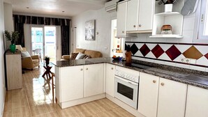 Una cocina moderna con armarios blancos, encimera de granito y salpicadero de azulejos.
