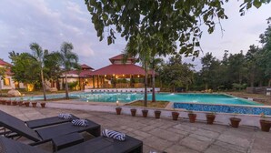 Uma área à beira da piscina com espreguiçadeiras e um espaço de estar coberto.