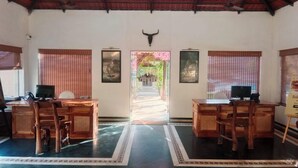 Um quarto espaçoso com teto alto, duas mesas de madeira com computadores, uma decoração de cabeça de touro e quadros nas paredes.