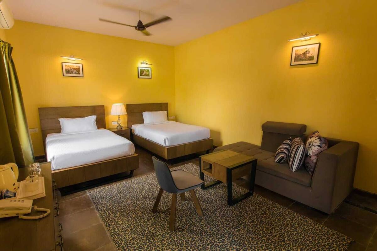 Una habitación de hotel con dos camas, un sofá, una mesita y una silla.