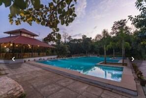 Un espace piscine doté d’un coin salon abrité et d’un pavillon.
