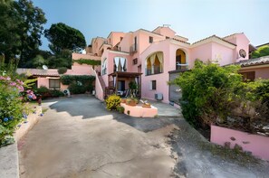 Una villa rosa con patio, antena parabólica y plantas en macetas.