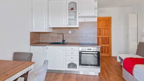 Een compacte keuken met witte kastjes, een ingebouwde oven en een houten aanrecht.