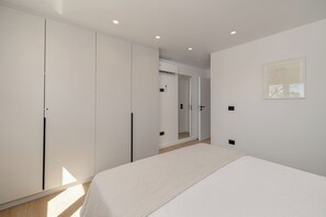 A bedroom with a bed, white wardrobe, and a framed picture on the wall. - Olyan Seaside Villa (Argostoli)