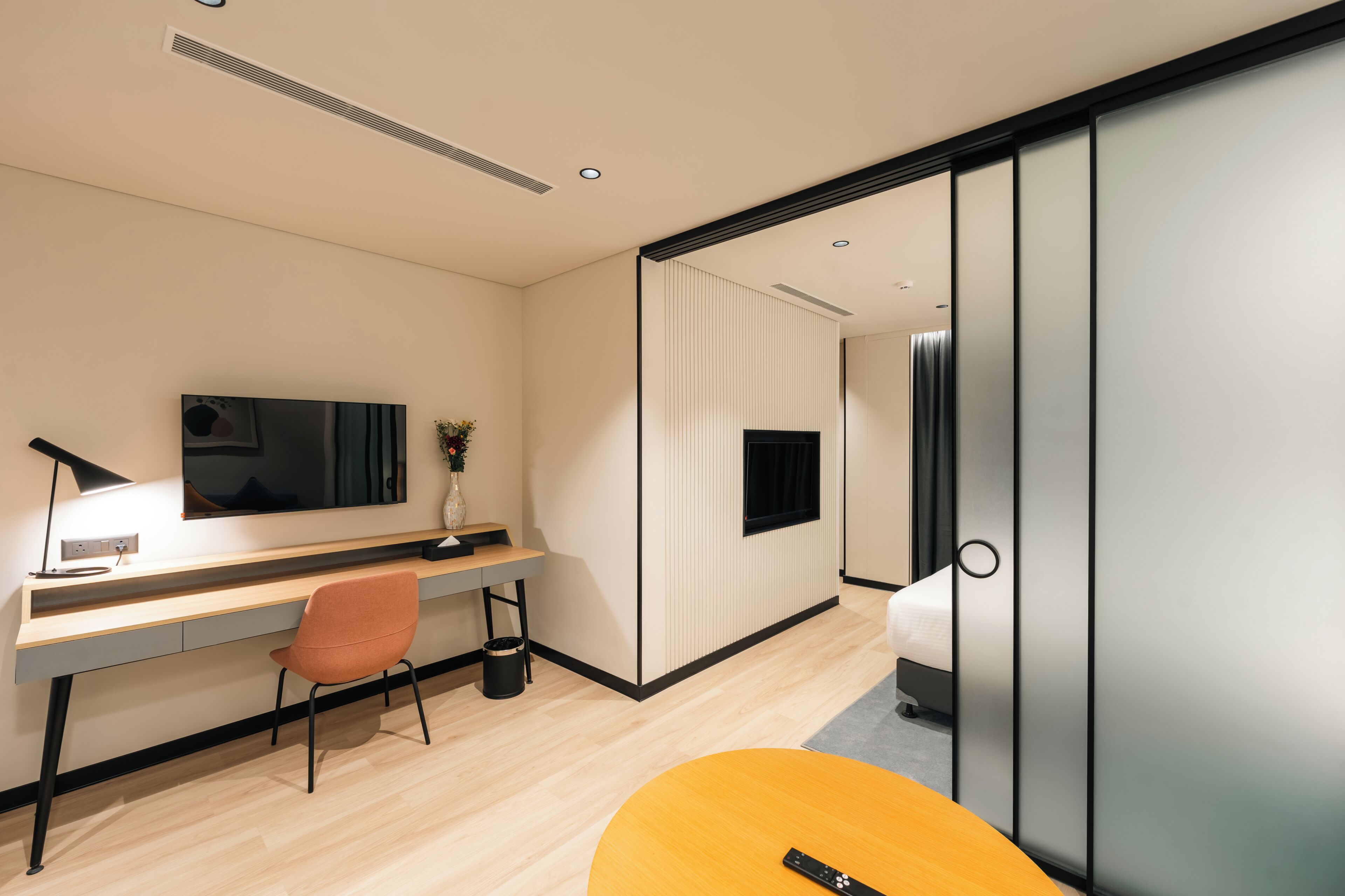 Una habitación de hotel moderna con escritorio, silla, televisor y cama.