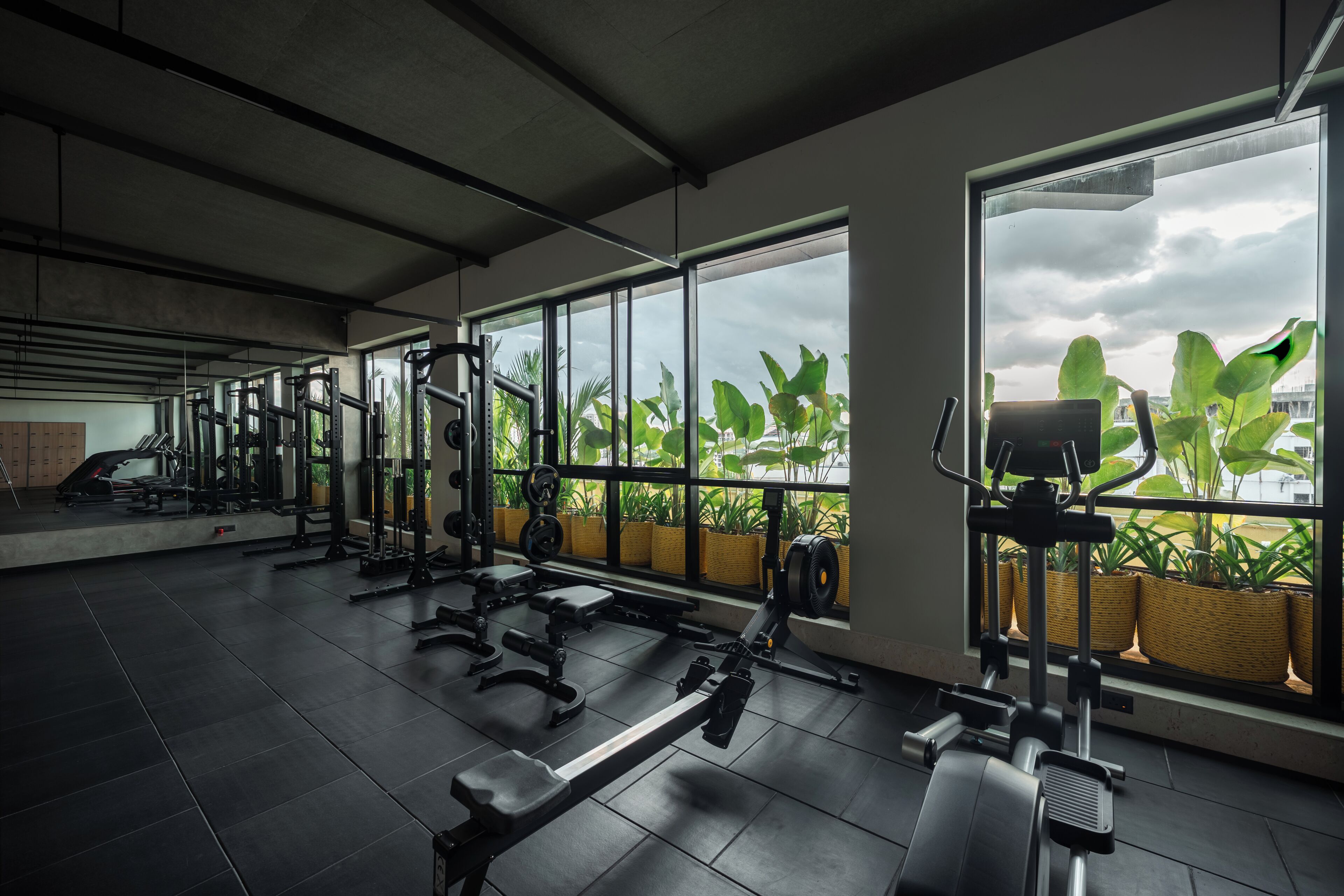 Ein Fitnessstudio mit Trainingsgeräten, großen Fenstern und Topfpflanzen.