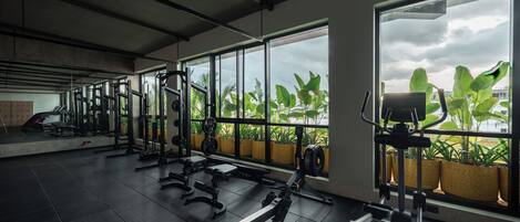 Ein Fitnessstudio mit Trainingsgeräten, großen Fenstern und Topfpflanzen.