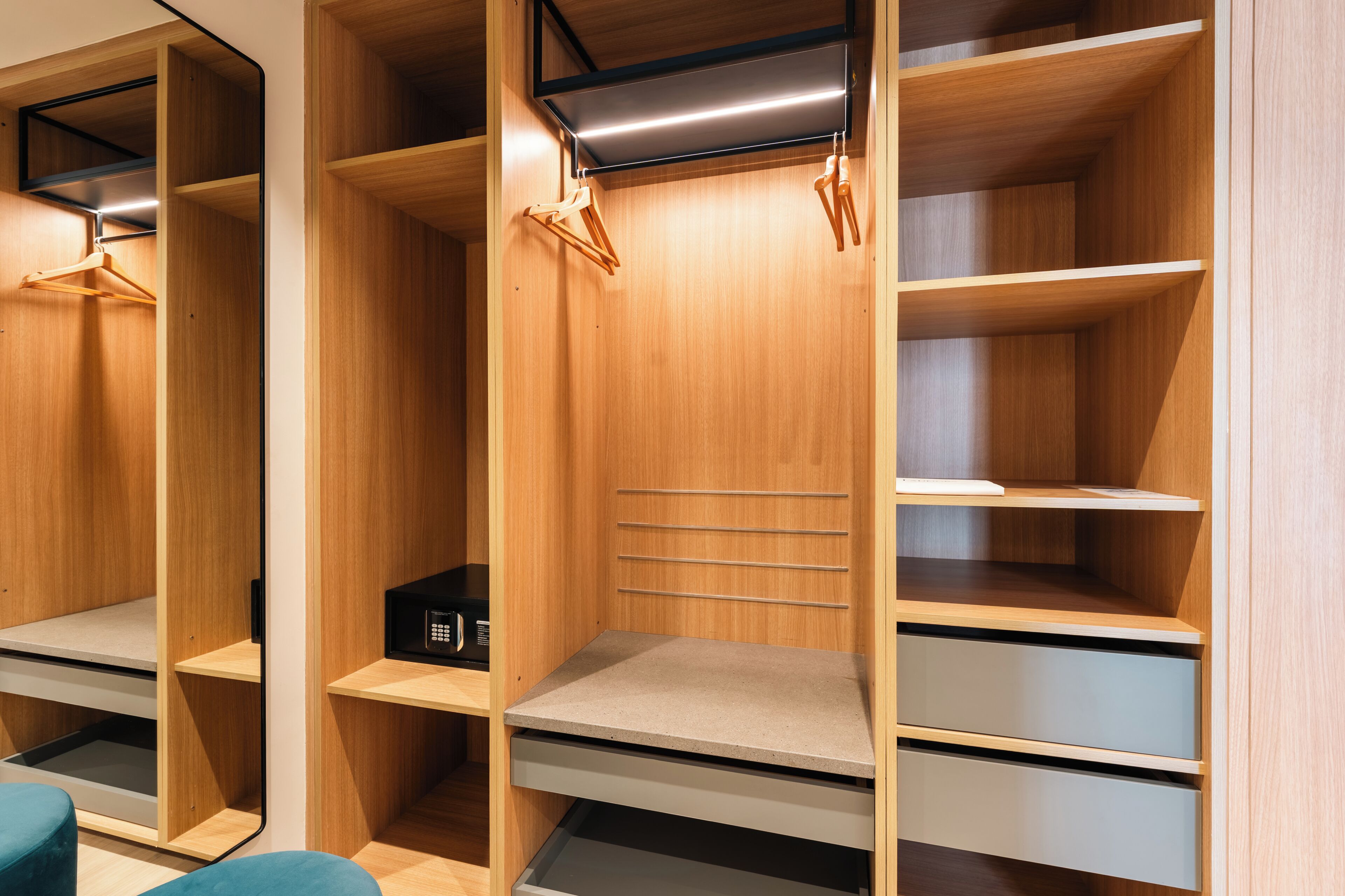 A modern closet with wooden shelving, a hanging rack, and a microwave.