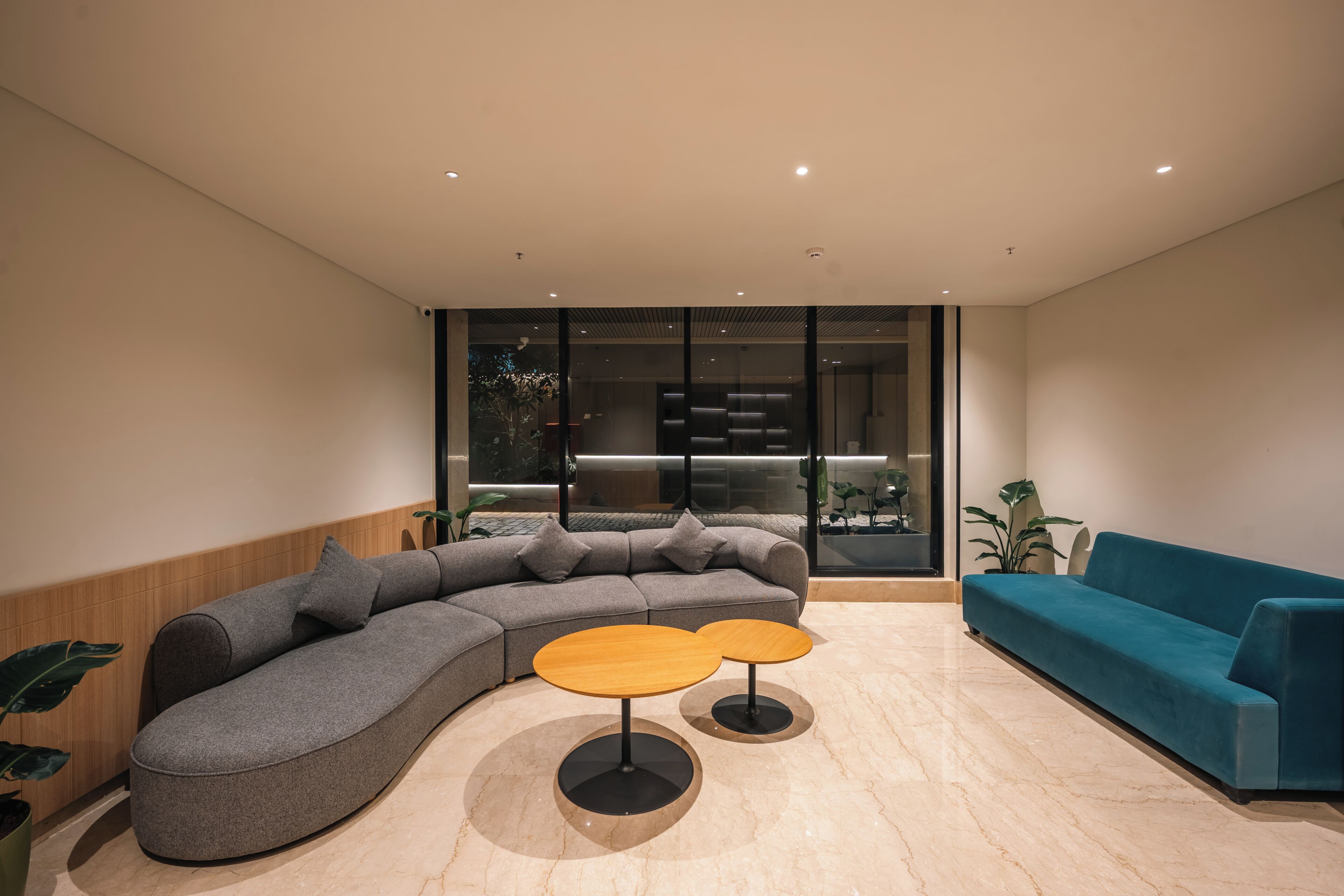 A modern living room with a sectional sofa, a blue couch, and two round tables.