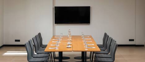A conference room with a long table, chairs, and a flat-screen TV on the wall.