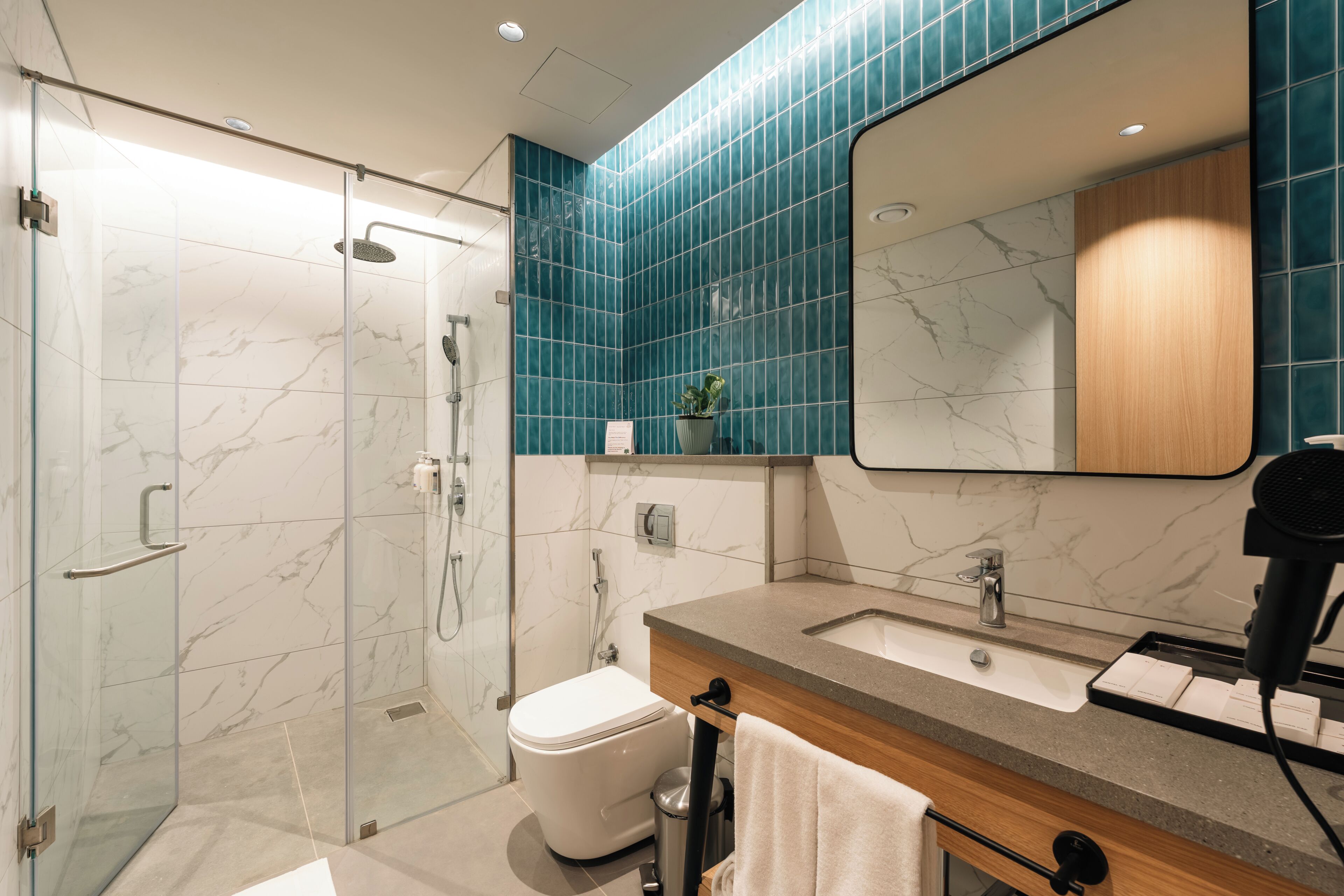 A modern bathroom with a glass shower enclosure, a white toilet, a sink with a mirror, and a towel rack.
